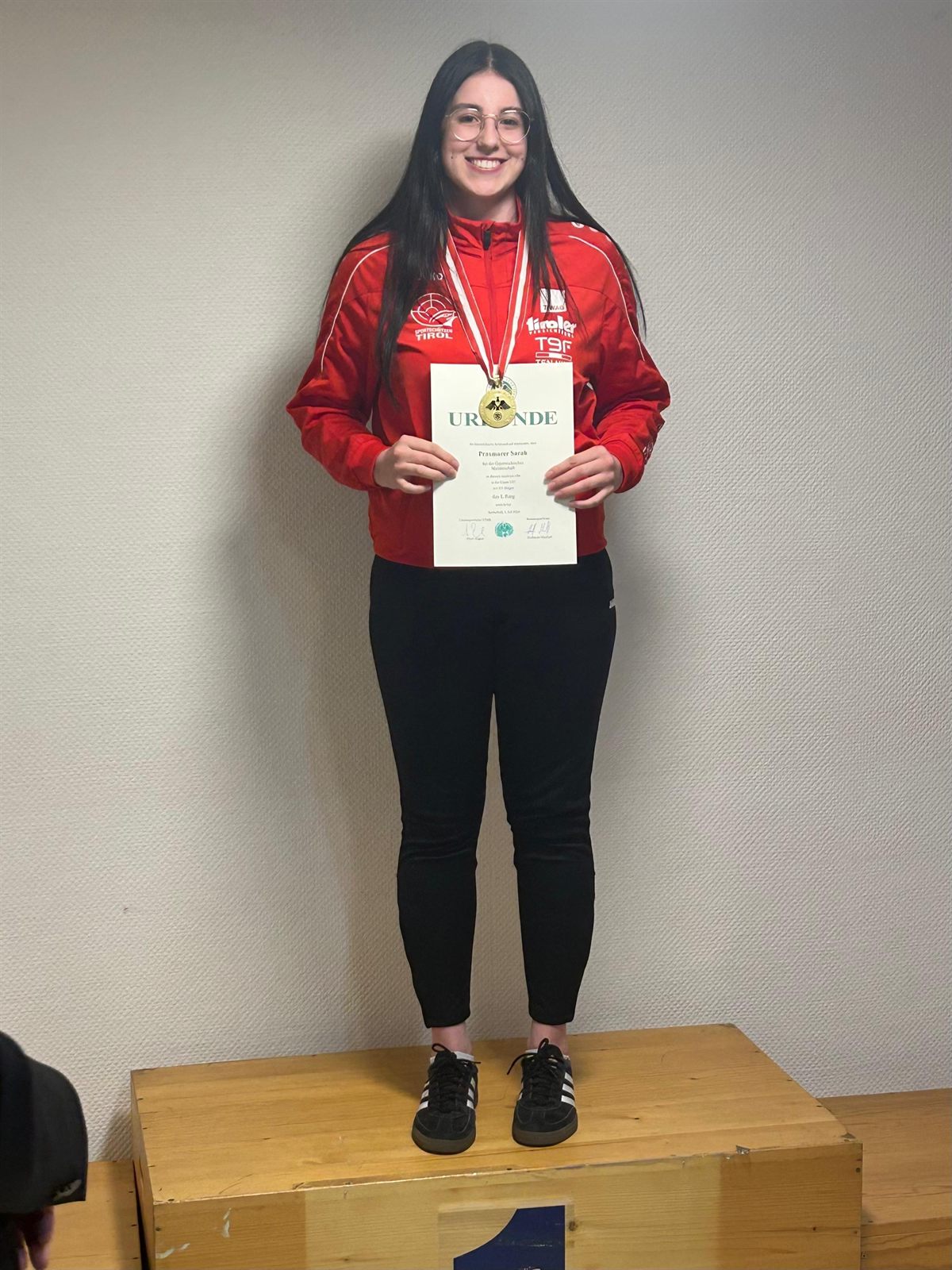 Sarah Praxmarer von der SG Münster auf dem Siegerpodest mit Goldmedaille und Urkunde